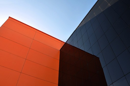 Black and orange modern buildings reflect each other. View from below.